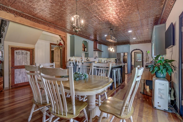 dining area featuring a chandelier, brick ceiling, and dark wood-type flooring