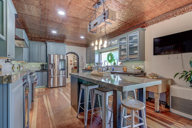 kitchen featuring tasteful backsplash, decorative light fixtures, dark stone countertops, a breakfast bar area, and stainless steel fridge