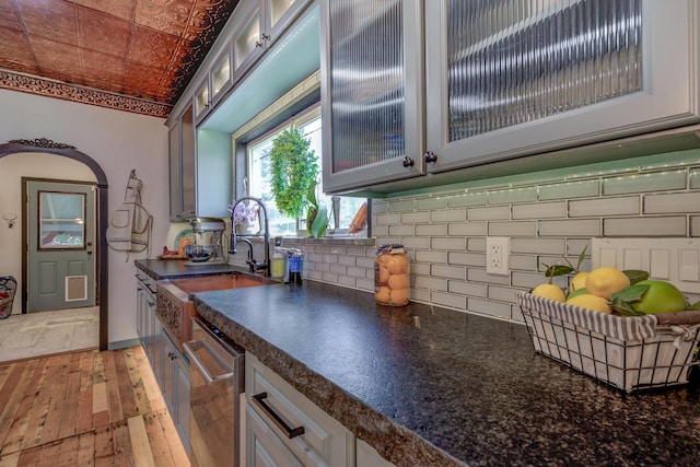 kitchen featuring sink, stainless steel dishwasher, tasteful backsplash, and light hardwood / wood-style flooring