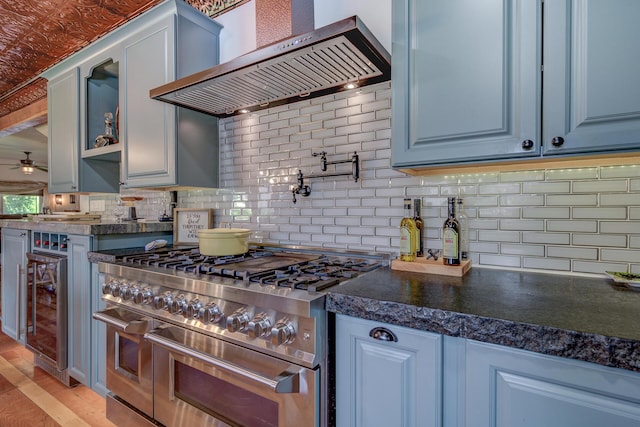 kitchen featuring wine cooler, ceiling fan, wall chimney exhaust hood, backsplash, and range with two ovens