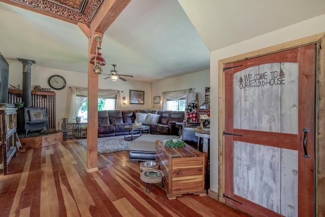 living room with wood-type flooring, ceiling fan, and a wood stove