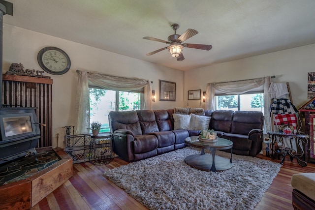 living room featuring a wood stove, ceiling fan, and hardwood / wood-style flooring