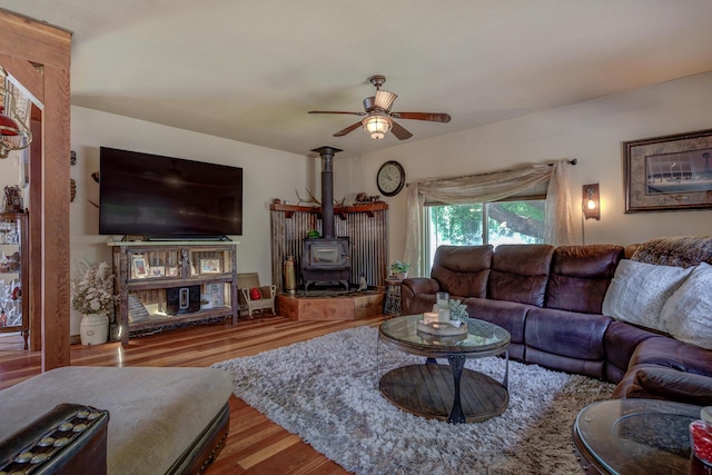 living room with a wood stove, ceiling fan, and light hardwood / wood-style floors