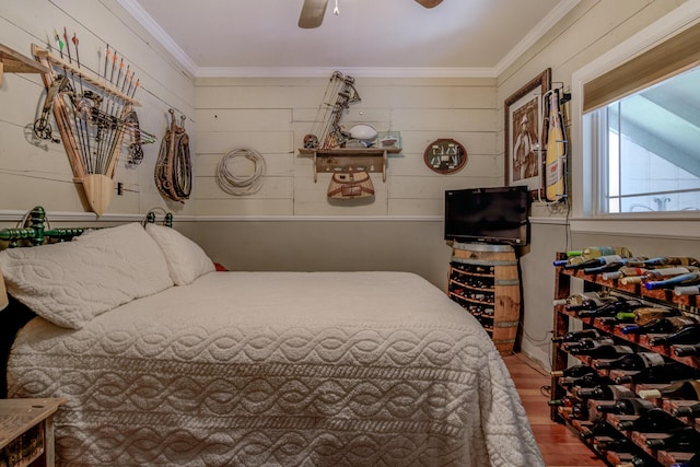 bedroom featuring hardwood / wood-style flooring, wood walls, crown molding, and ceiling fan