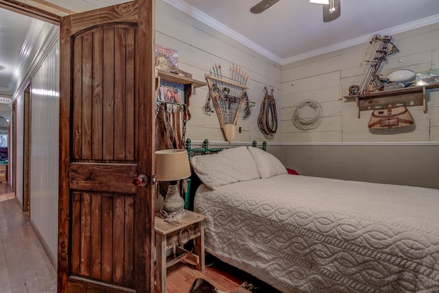 bedroom featuring ceiling fan, crown molding, wooden walls, and wood-type flooring