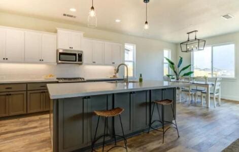 kitchen featuring a kitchen island with sink, stainless steel microwave, light wood finished floors, and a sink