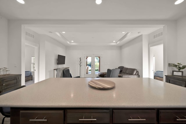 kitchen with dark brown cabinetry, french doors, and a raised ceiling