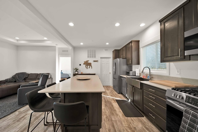 kitchen with dark brown cabinets, light wood-type flooring, appliances with stainless steel finishes, and a kitchen island