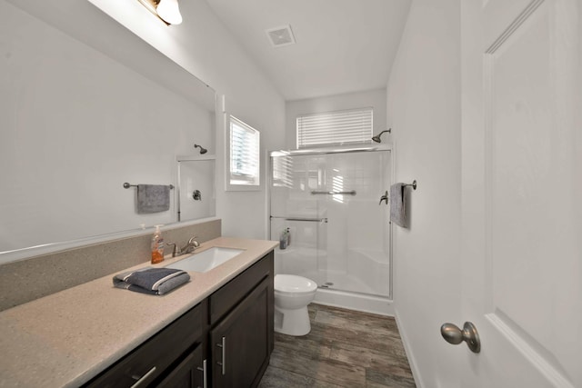 bathroom with hardwood / wood-style floors, vanity, walk in shower, and toilet