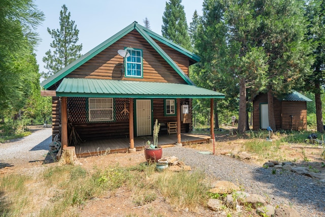 log cabin featuring metal roof, driveway, and an outdoor structure