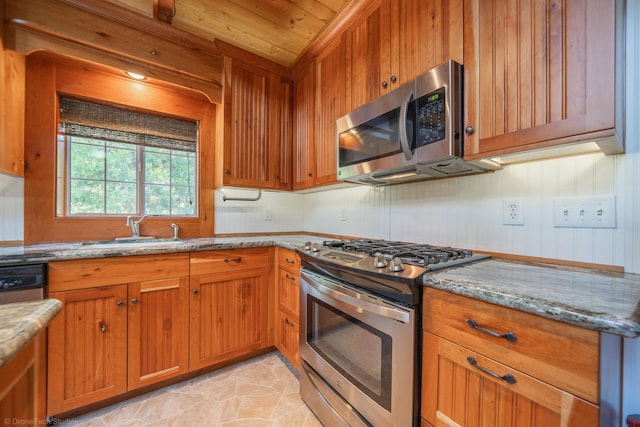 kitchen featuring brown cabinetry, wood ceiling, appliances with stainless steel finishes, light stone counters, and a sink