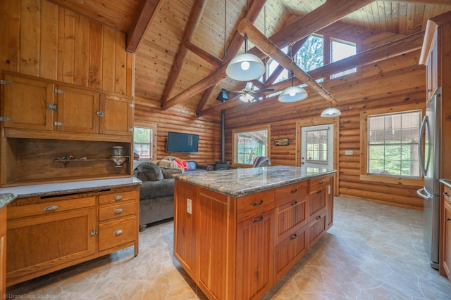 kitchen with brown cabinetry, light stone counters, open floor plan, freestanding refrigerator, and a center island