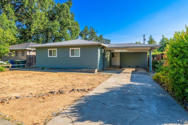 ranch-style house featuring concrete driveway, a carport, and fence