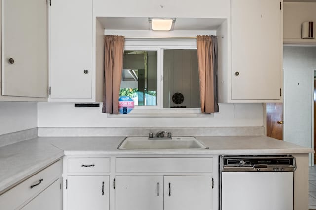 kitchen with sink, white dishwasher, and white cabinetry