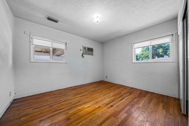 empty room featuring an AC wall unit and hardwood / wood-style flooring