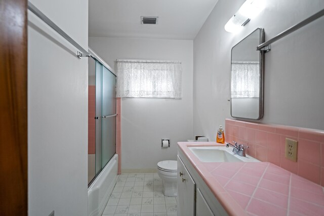 full bathroom with a healthy amount of sunlight, toilet, vanity, and enclosed tub / shower combo