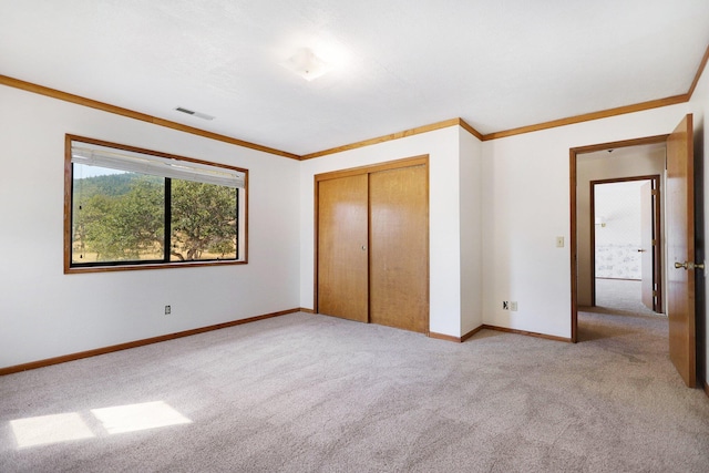 unfurnished bedroom featuring ornamental molding, a closet, and light carpet