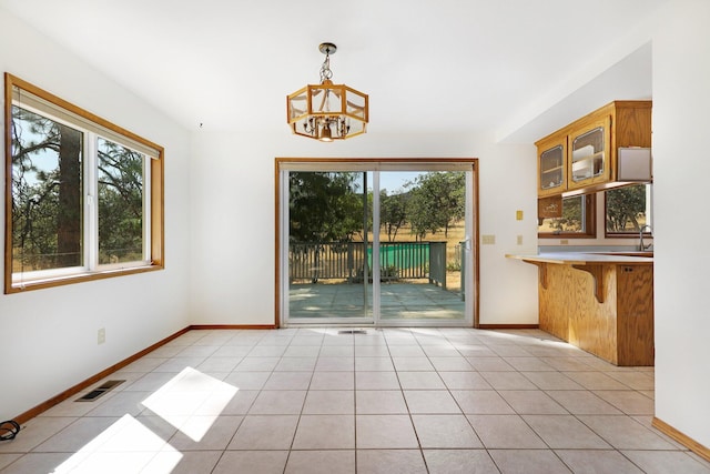 unfurnished dining area with light tile patterned floors, sink, and an inviting chandelier