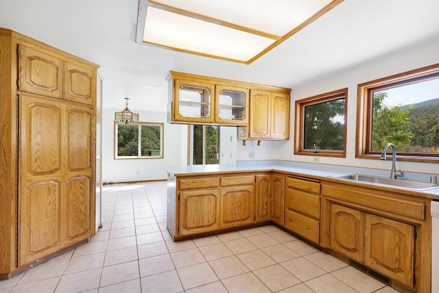 kitchen with kitchen peninsula, light tile patterned flooring, dishwashing machine, and sink