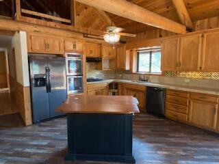 kitchen with beam ceiling, ceiling fan, dark hardwood / wood-style floors, appliances with stainless steel finishes, and decorative backsplash