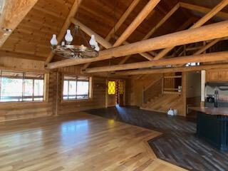 unfurnished living room with wooden ceiling, vaulted ceiling, light hardwood / wood-style flooring, and an inviting chandelier