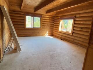 spare room with beamed ceiling, wooden ceiling, and log walls