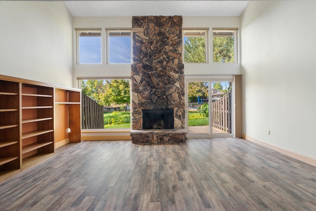 unfurnished living room featuring a high ceiling, hardwood / wood-style floors, and a fireplace