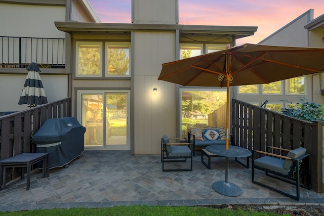 patio terrace at dusk featuring grilling area and an outdoor hangout area