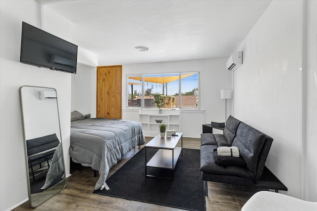 bedroom featuring a wall mounted air conditioner and hardwood / wood-style flooring