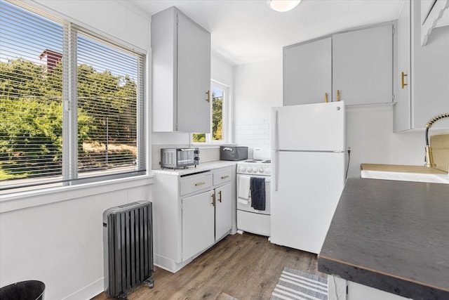 kitchen featuring radiator, white cabinetry, sink, hardwood / wood-style flooring, and white appliances