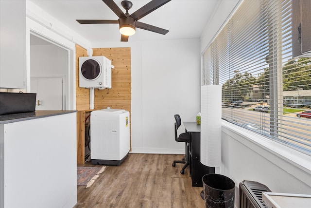 home office with stacked washer and dryer, wood-type flooring, ceiling fan, and wooden walls