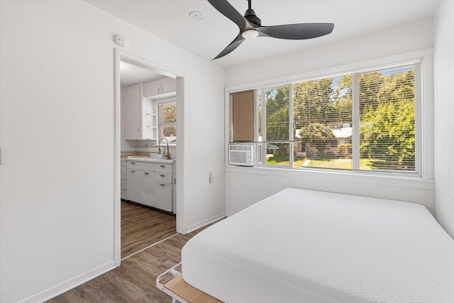 bedroom with cooling unit, sink, hardwood / wood-style floors, and multiple windows