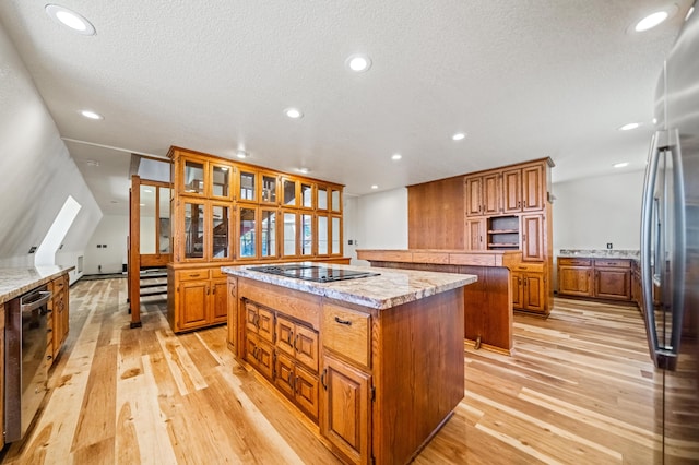 kitchen with light hardwood / wood-style floors, appliances with stainless steel finishes, a center island, and a textured ceiling