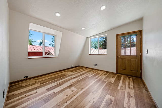 interior space with lofted ceiling, light hardwood / wood-style floors, and a textured ceiling