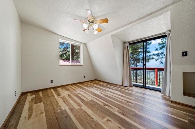 interior space with ceiling fan, a textured ceiling, light hardwood / wood-style flooring, and lofted ceiling