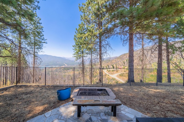 view of yard with an outdoor fire pit, a fenced backyard, and a mountain view