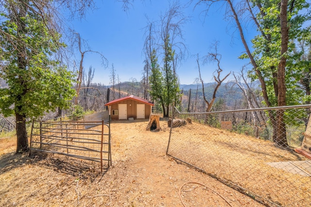 view of yard with a gate, fence, an outdoor structure, and a mountain view