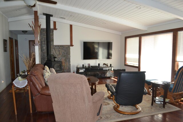 living room featuring hardwood / wood-style floors, a wood stove, lofted ceiling with beams, and ceiling fan