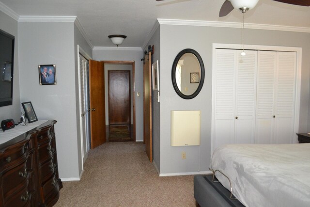 carpeted bedroom with ceiling fan, a barn door, a closet, and crown molding