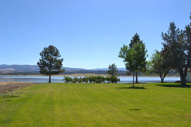 view of home's community featuring a water and mountain view and a lawn