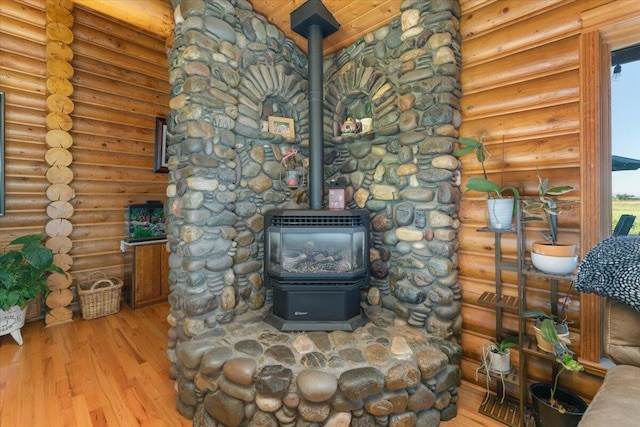 interior details featuring log walls, a wood stove, and hardwood / wood-style flooring