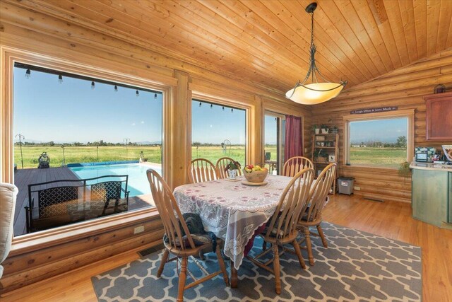 dining room featuring rustic walls, lofted ceiling, and light hardwood / wood-style floors