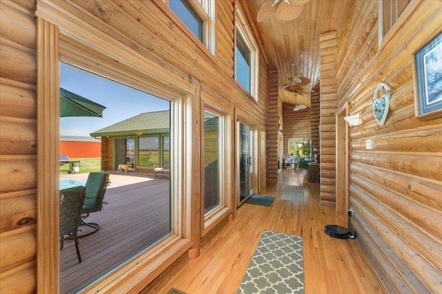 doorway to outside featuring light wood-type flooring, log walls, ceiling fan, a high ceiling, and wood ceiling