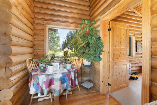 dining area featuring log walls and light hardwood / wood-style floors