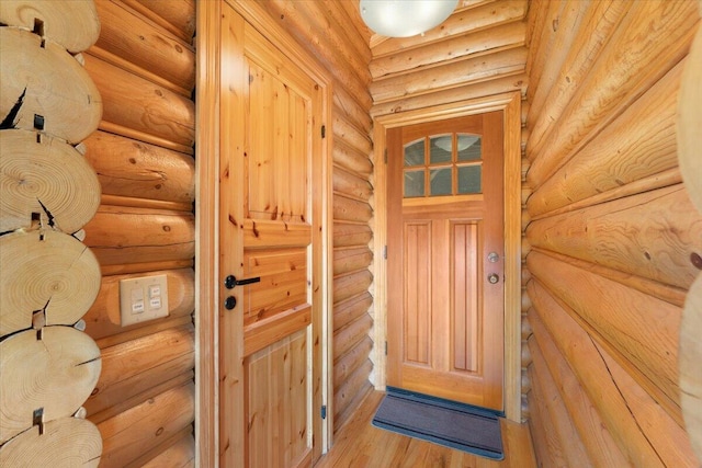 doorway with light wood-type flooring and rustic walls