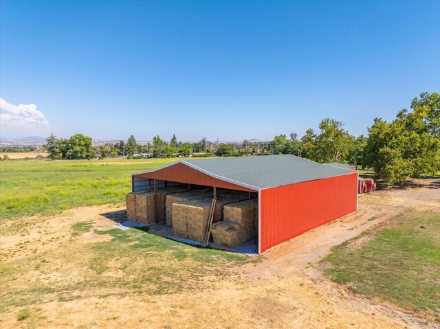 view of outbuilding featuring a rural view and a yard