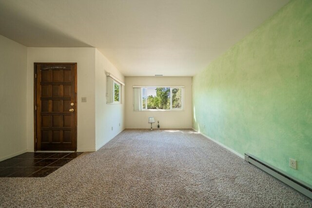 carpeted spare room with a baseboard heating unit