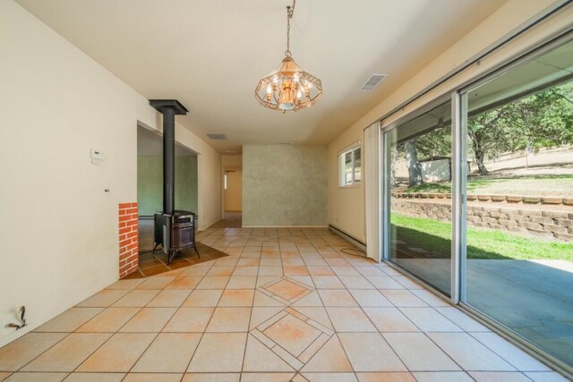 interior space with light tile patterned flooring, a wood stove, and a chandelier