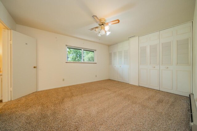 unfurnished bedroom featuring ceiling fan, carpet floors, and two closets