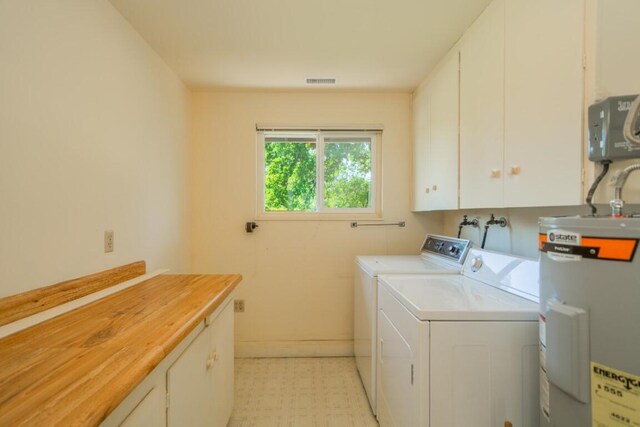 clothes washing area featuring cabinets, washing machine and dryer, and water heater